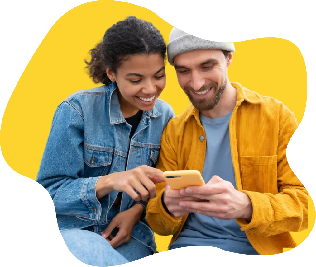 Une jeune homme tenant son smartphone, regardant l'écran avec un sourire à côté d'une jeune femme souriant aussi en regardant l'écran.