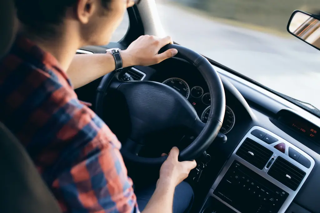 Jeune homme roulant au volant d'une voiture.
